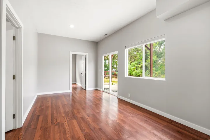 Spacious room featuring wood-finish flooring, light gray wall paint, and white trim
