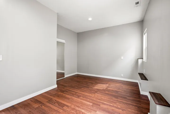 Spacious room featuring wood-finish flooring, light grey walls, and white trim