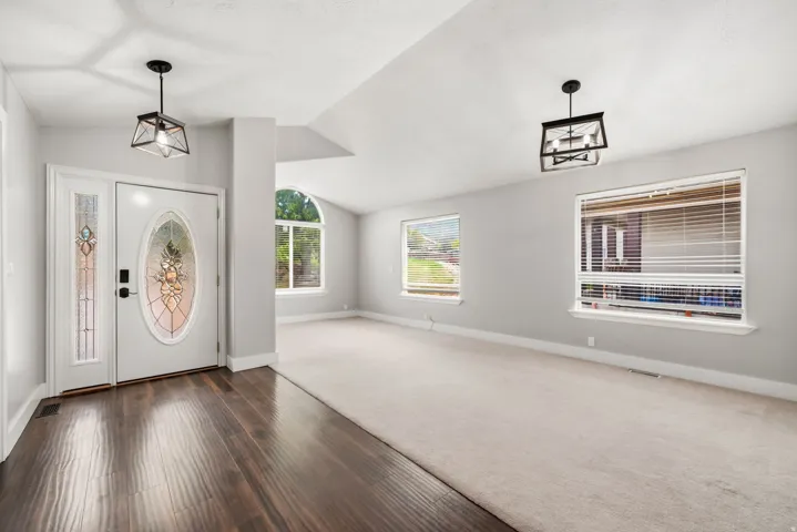 Entryway featuring dark wood-finish flooring, a white door with an oval stained-glass insert, and a sidelight with stained-glass panels