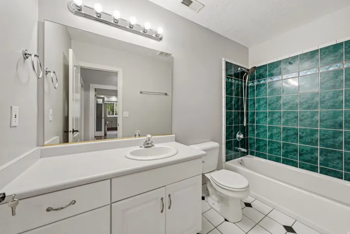 Bathroom featuring a white vanity with integrated sink, a large mirror, and a five-bulb vanity light fixture
