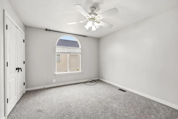 Room featuring a half-round top window, ceiling fan, and light gray wall finish