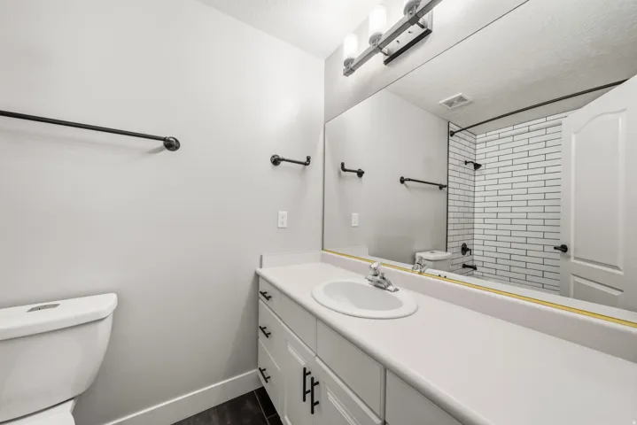 White vanity with integrated sink, white countertop, and dark-finish hardware