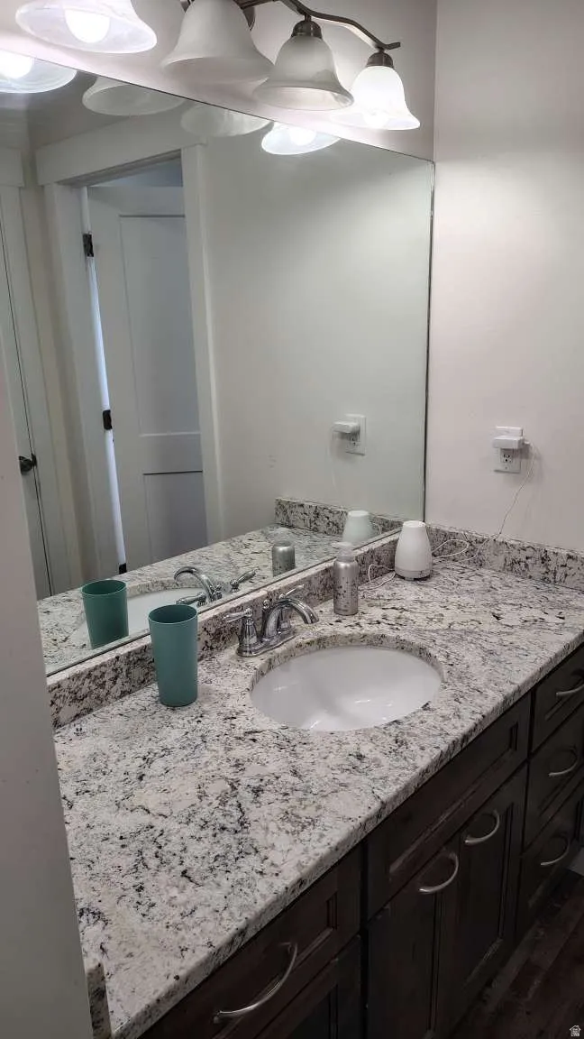 Vanity with an integrated oval sink, stone-finish countertop, dark wood-finish cabinetry, and a chrome faucet
