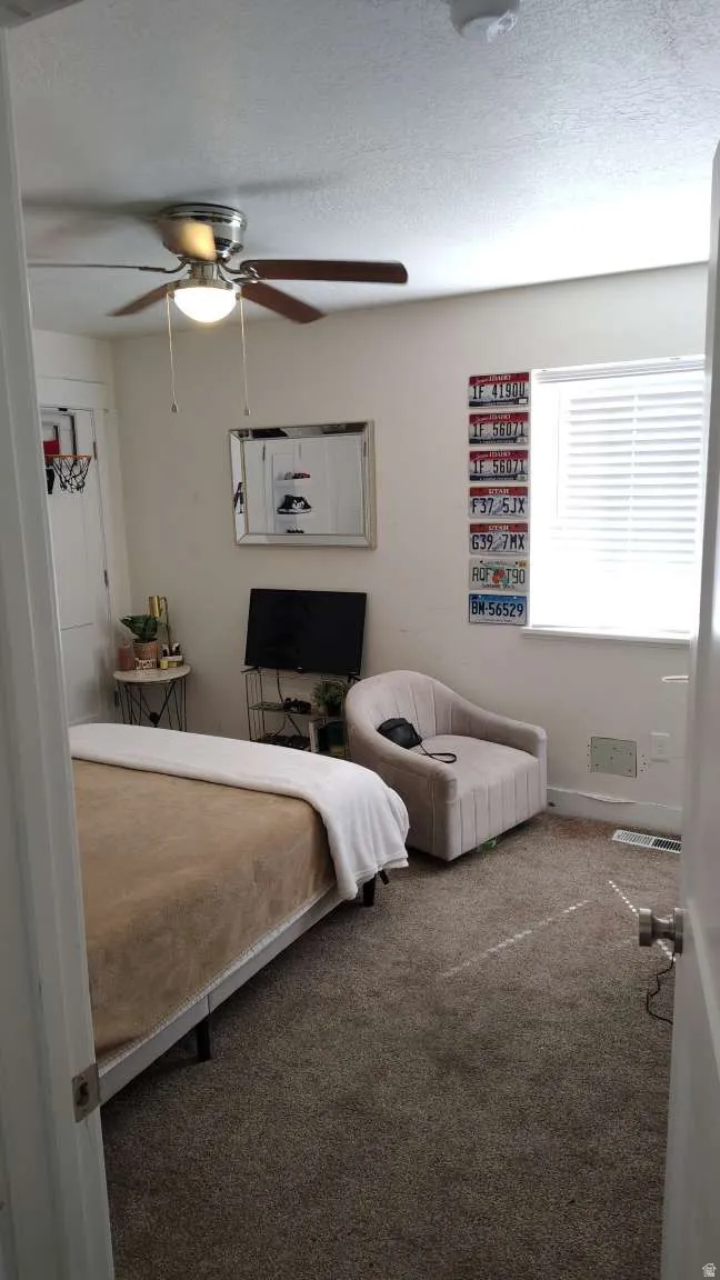 Ceiling fan with integrated lighting, window with blinds, wall-to-wall carpeting, and white painted walls