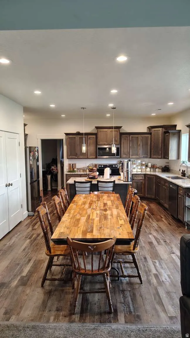 Kitchen featuring dark wood cabinetry, stainless steel appliances, and a central island with bar seating