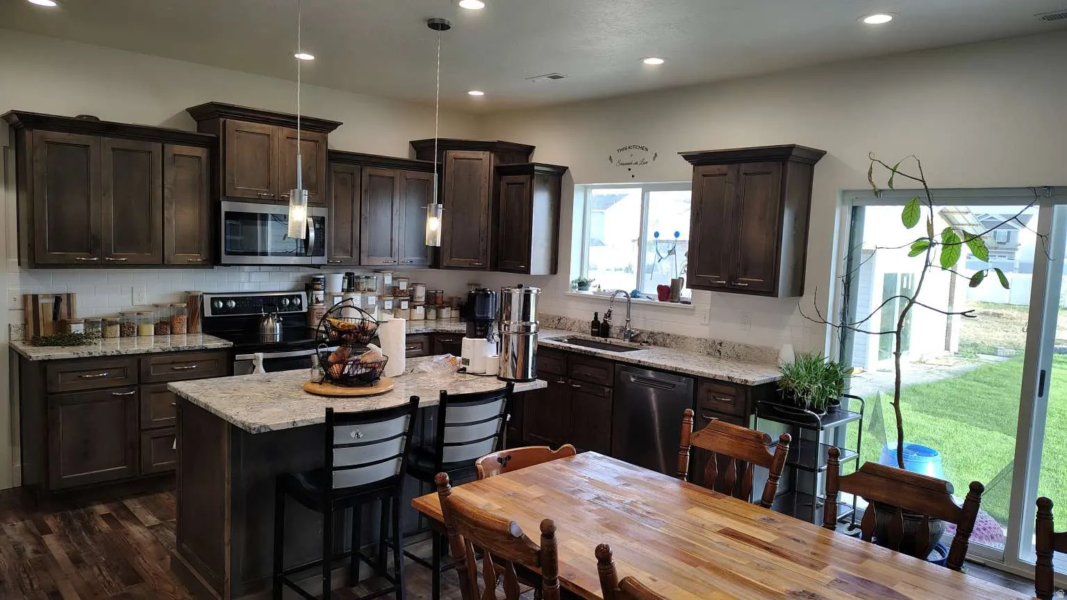 Well-appointed kitchen featuring dark wood cabinetry, light-toned countertops, and a subway tile backsplash