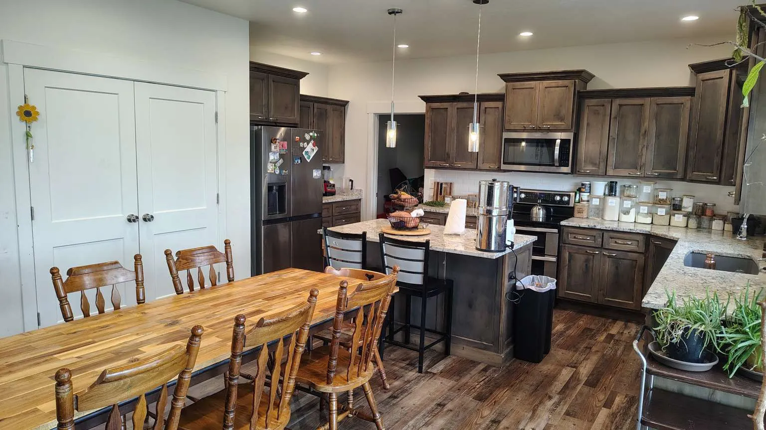 Kitchen featuring dark wood-finish cabinetry, granite countertops, stainless steel appliances, and wood-finish flooring