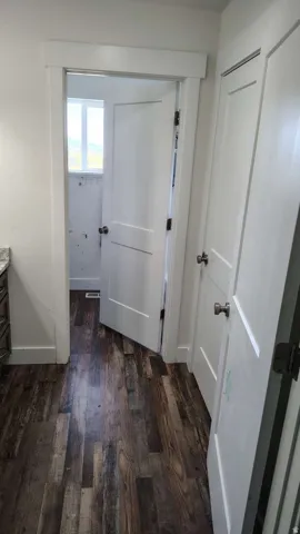 Wood-finish flooring with white trim and paneled doors