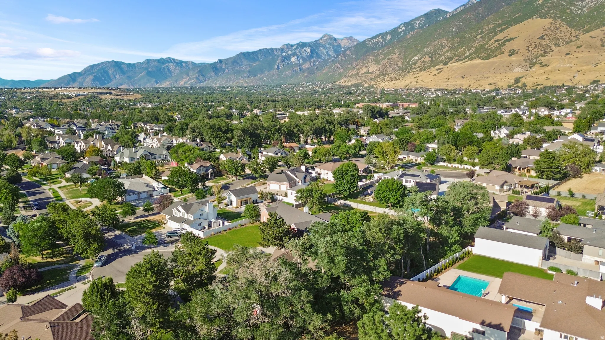 Expansive residential area featuring a diverse collection of homes, mature trees, and mountainous terrain in the background