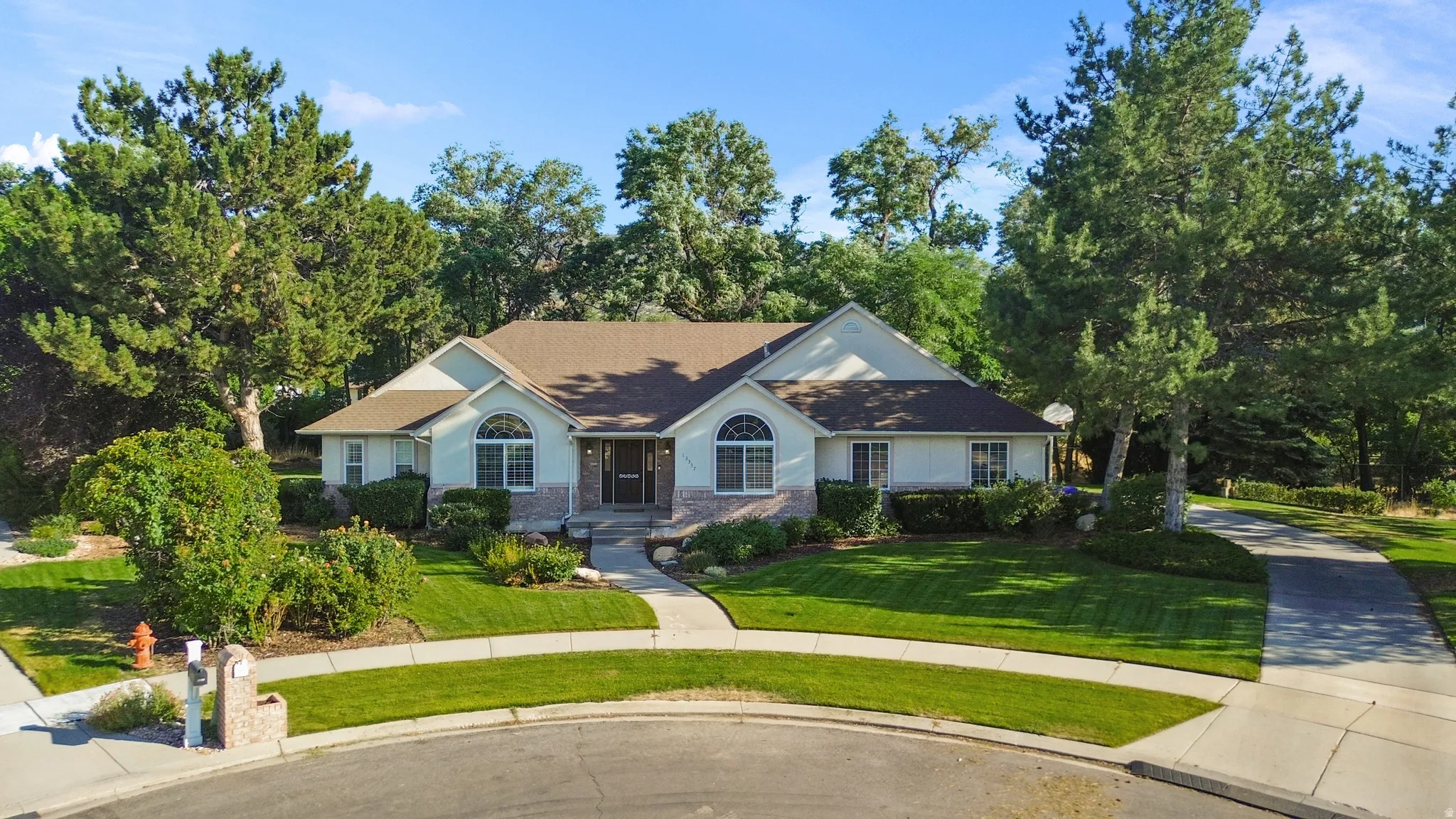 Single-story residence featuring a light-colored exterior with stone accents and a brown shingle roof