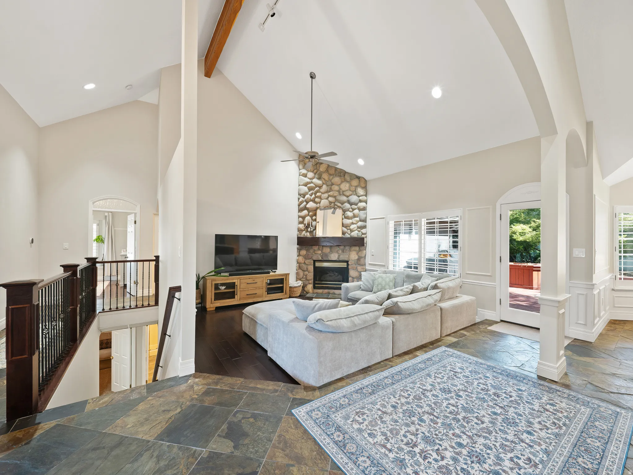 Vaulted ceilings in a spacious living area featuring a floor-to-ceiling stone fireplace