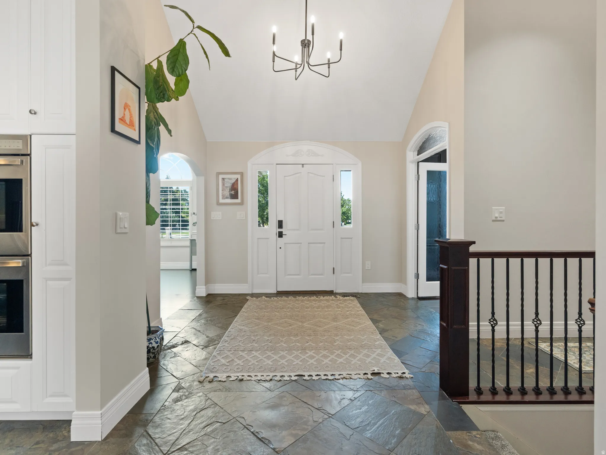 Vaulted entryway featuring slate tile flooring and a decorative chandelier