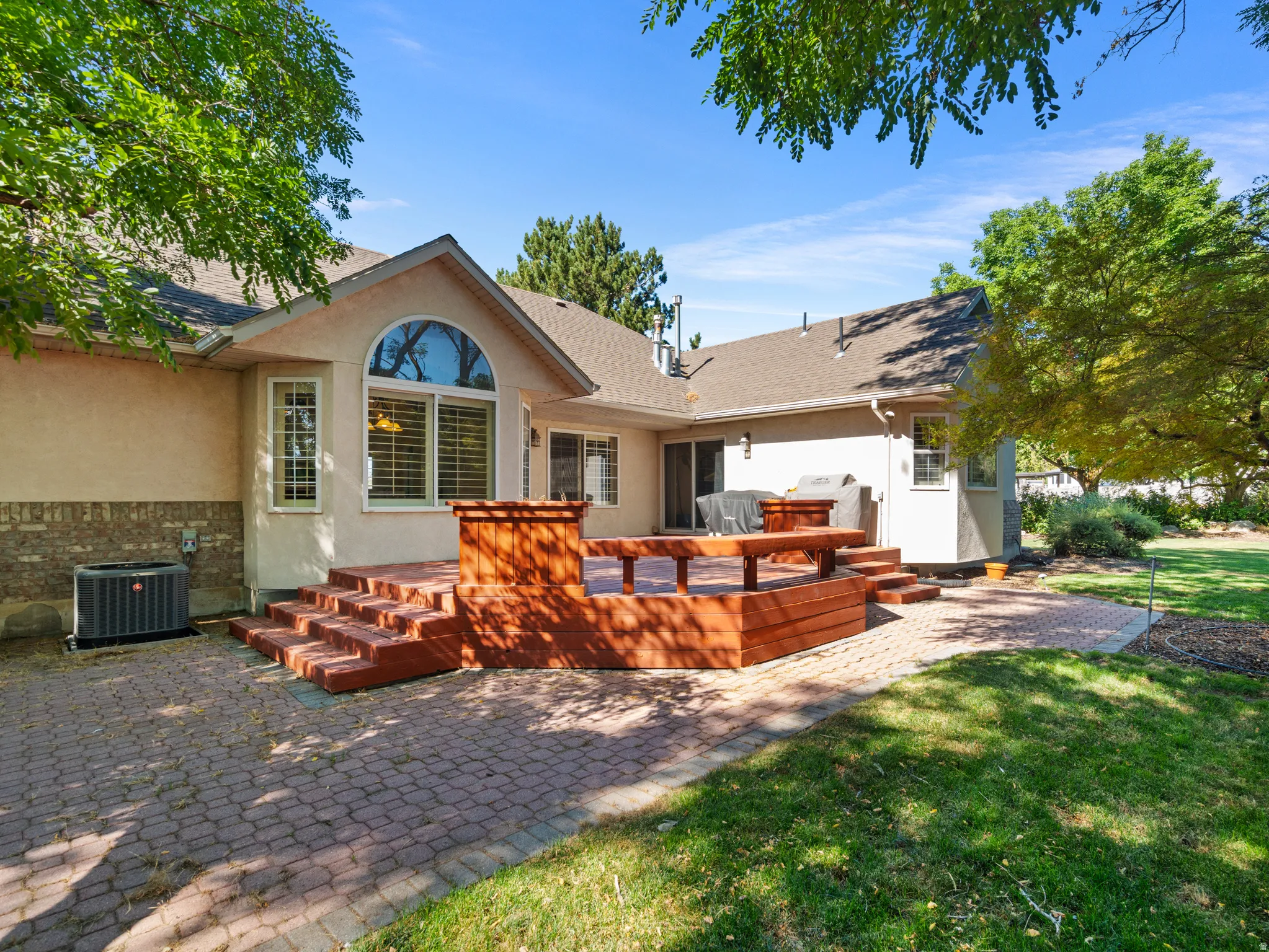 Expansive backyard featuring a multi-level wood deck, a patio with brick pavers, and a manicured lawn