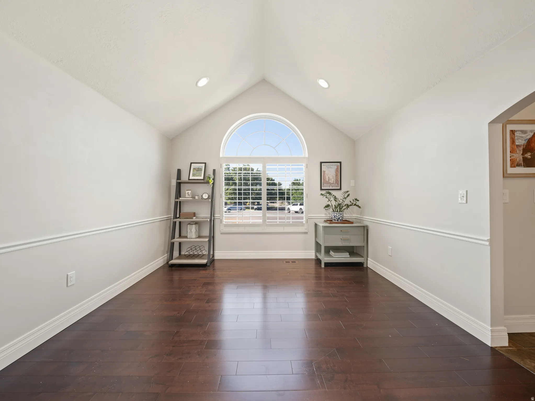 Vaulted ceiling with recessed lighting, arched transom window, wood-finish flooring, and chair rail molding