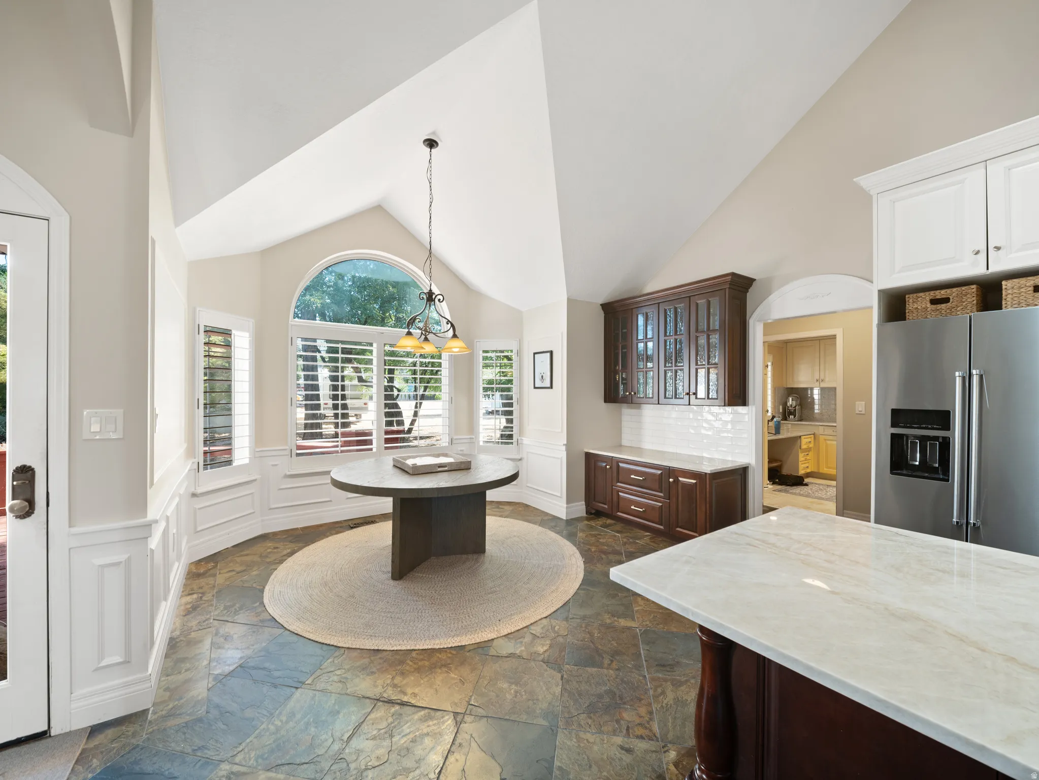 Vaulted ceiling kitchen nook featuring a half-round window with plantation shutters