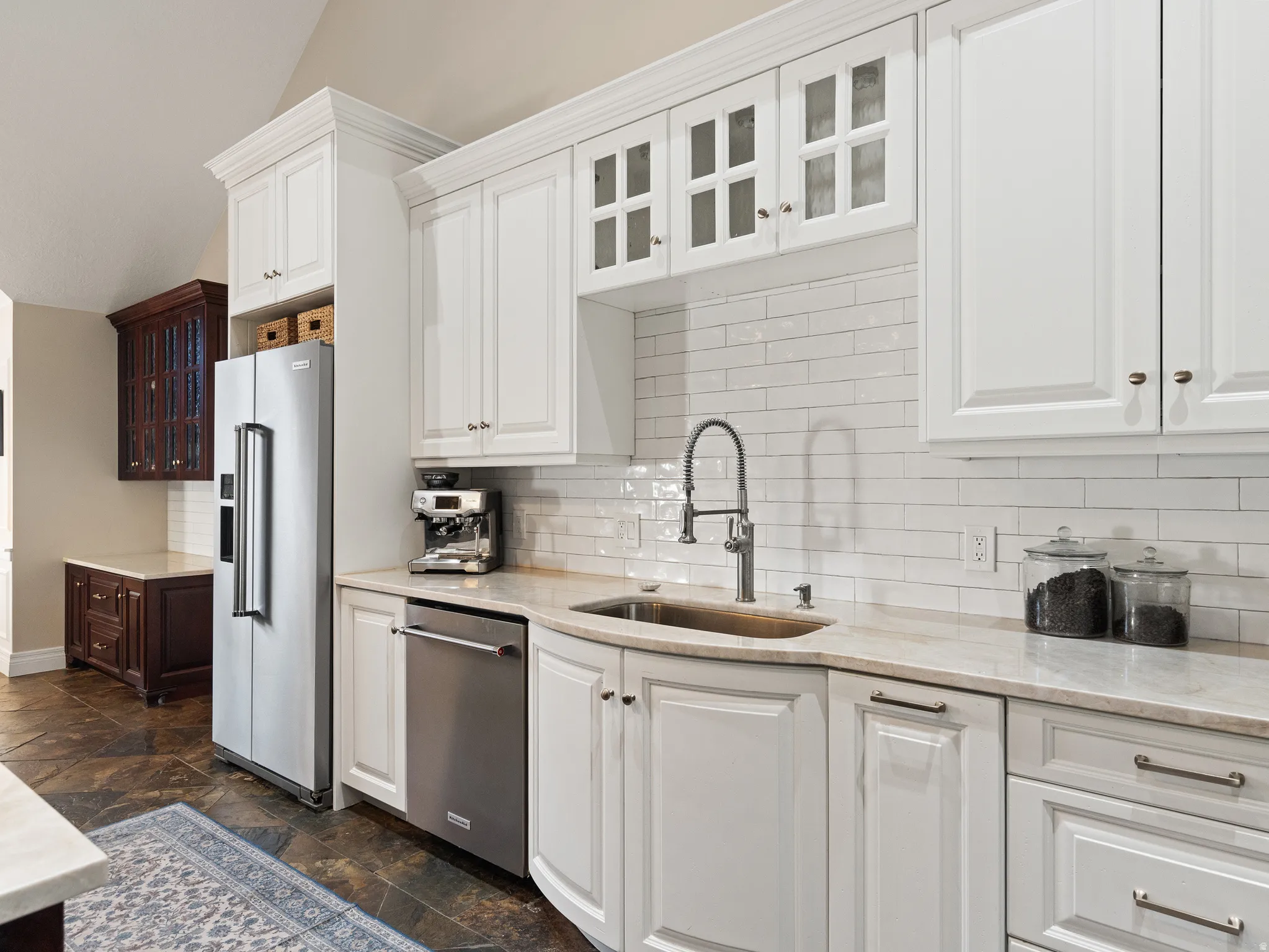 Kitchen featuring white shaker-style cabinetry with crown molding, subway tile backsplash, and light-toned countertops
