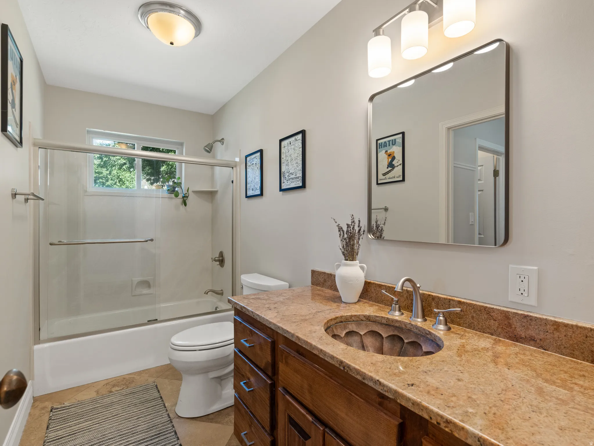 Wood-finish vanity featuring a stone countertop, an oval basin, and a brushed nickel faucet