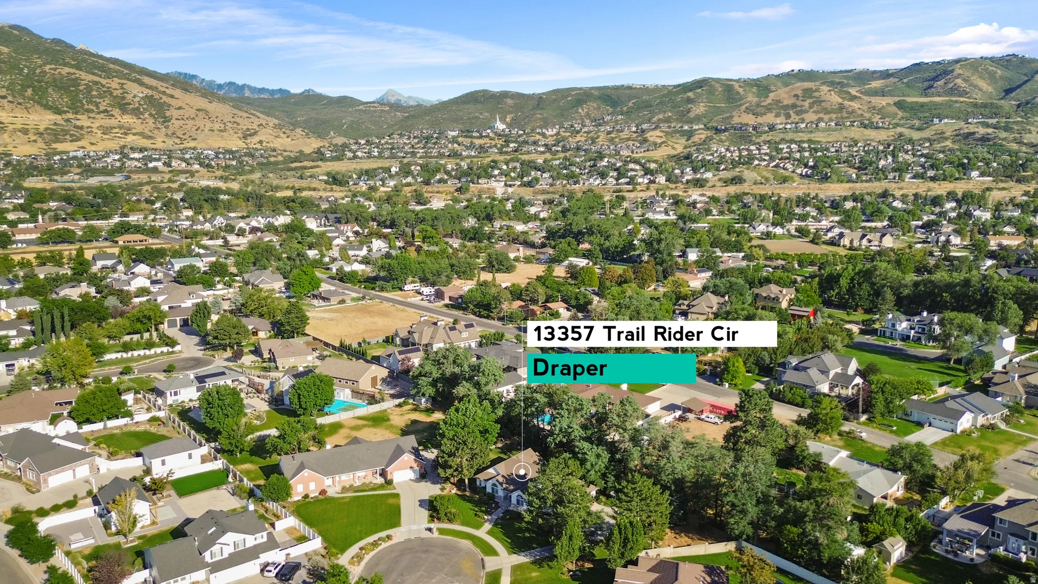 Expansive residential area featuring numerous single-family homes, mature trees, and a mountain backdrop