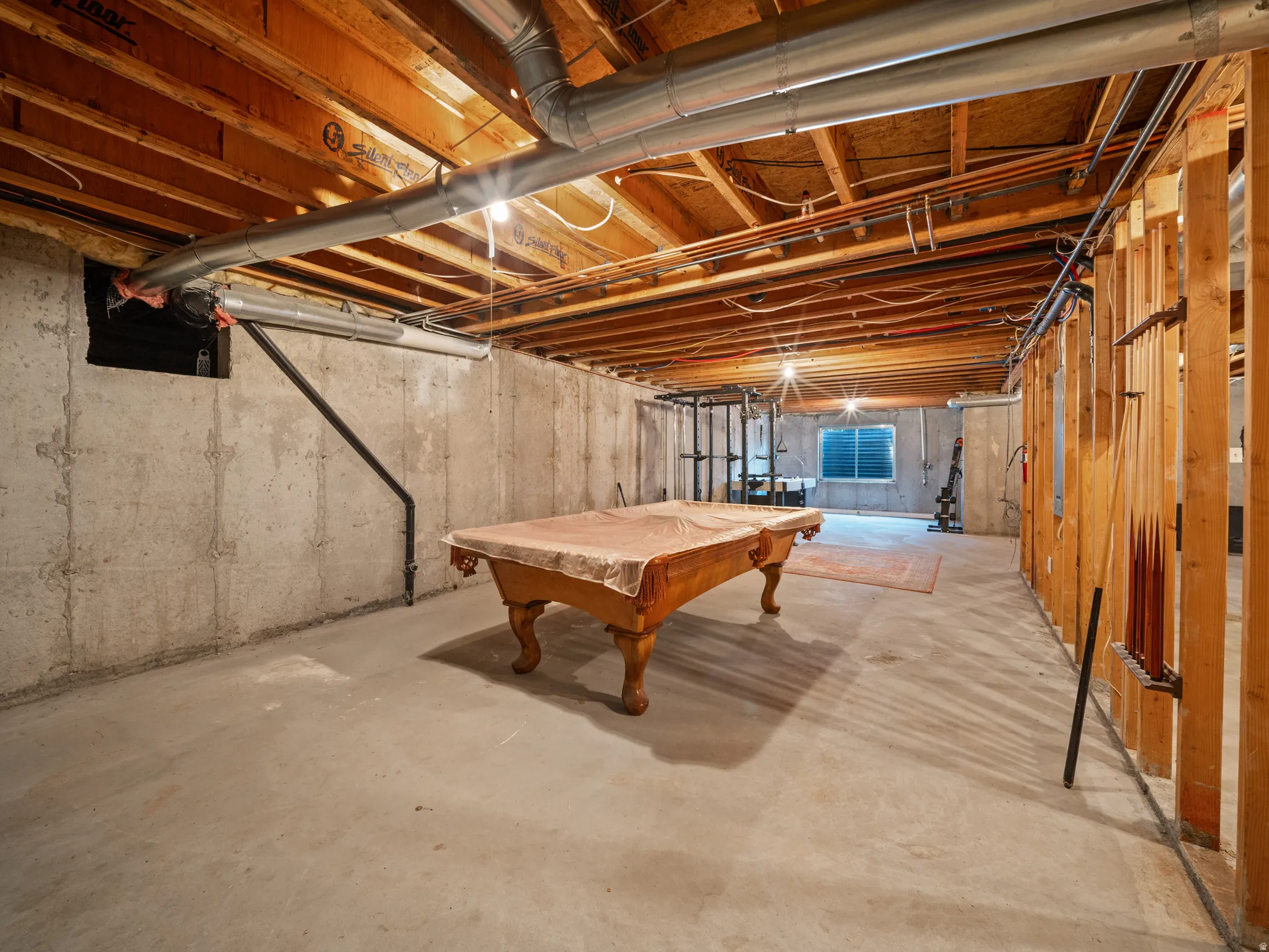 Unfinished basement featuring exposed wood joists, concrete foundation walls, and a concrete floor