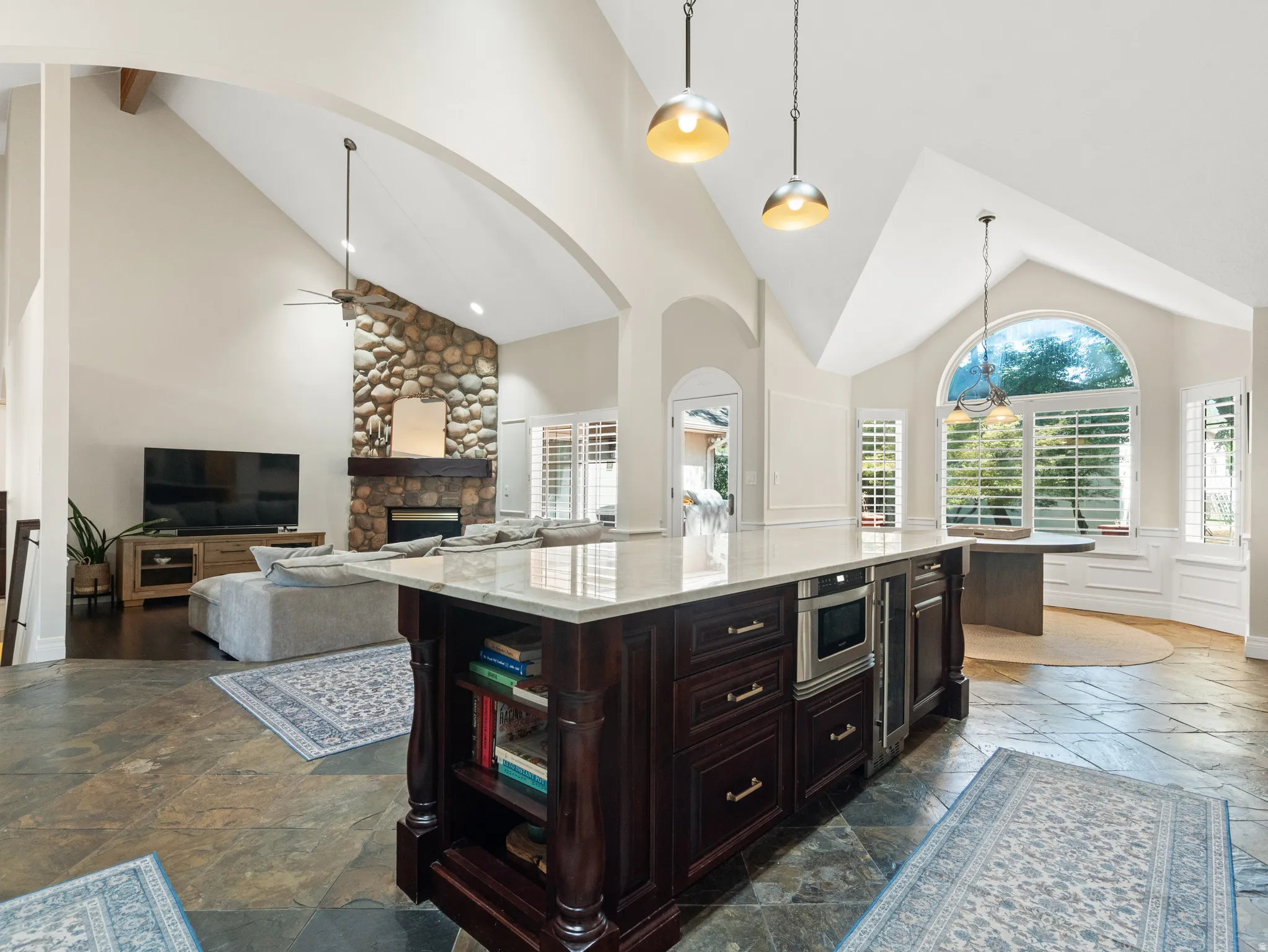 Kitchen island with dark wood cabinetry and stone countertop, featuring an integrated microwave and beverage refrigerator