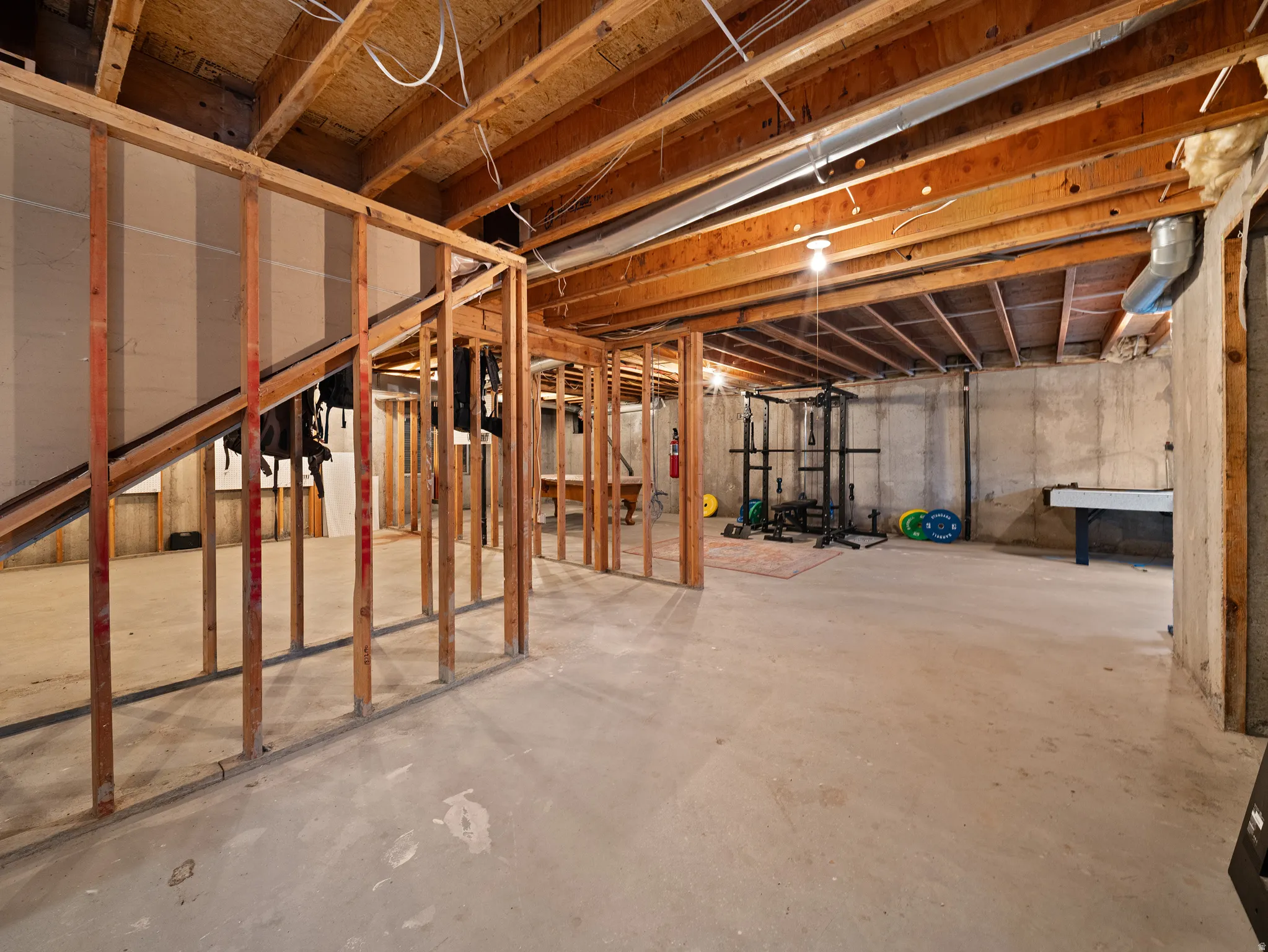 Unfinished basement featuring exposed wood joists and a concrete floor