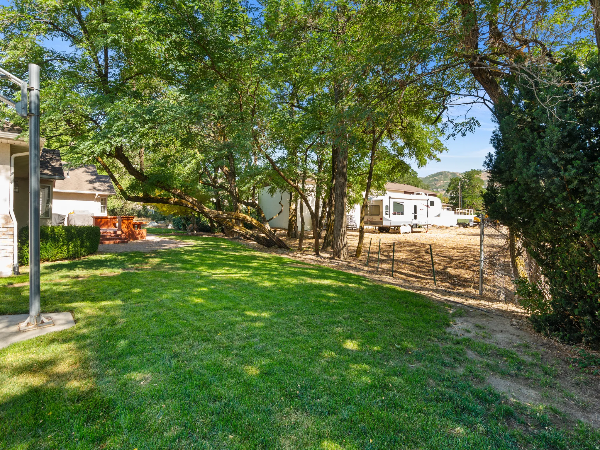 Expansive green lawn with mature trees providing shade