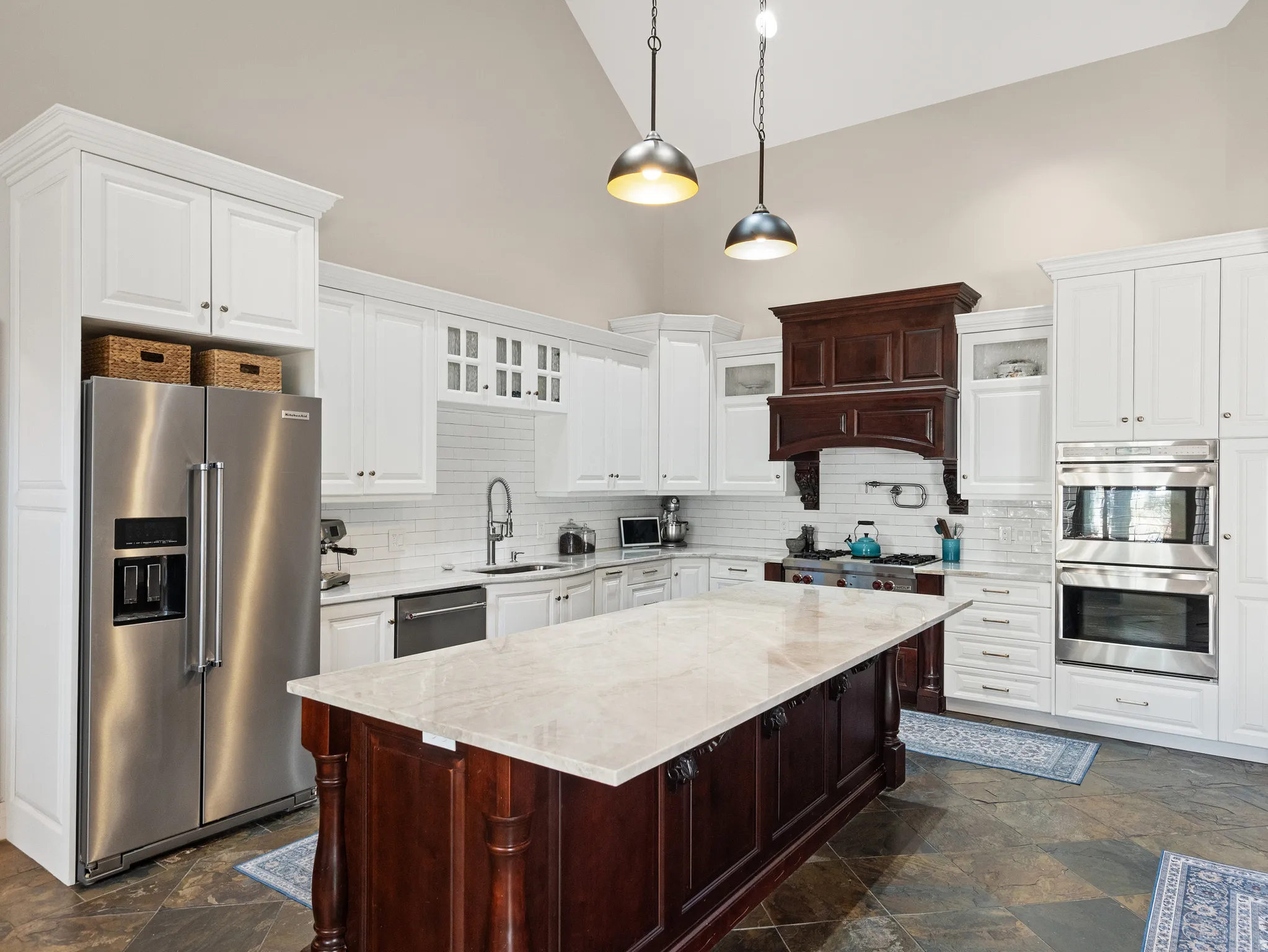 Kitchen featuring a large central island with a light-toned countertop, contrasting dark wood cabinetry, and pendant lighting
