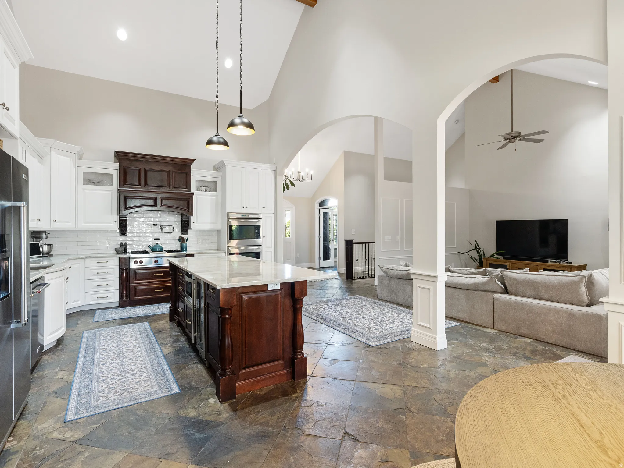 Spacious kitchen featuring an expansive center island with a light-toned countertop, contrasting dark wood cabinetry, and stainless steel appliances