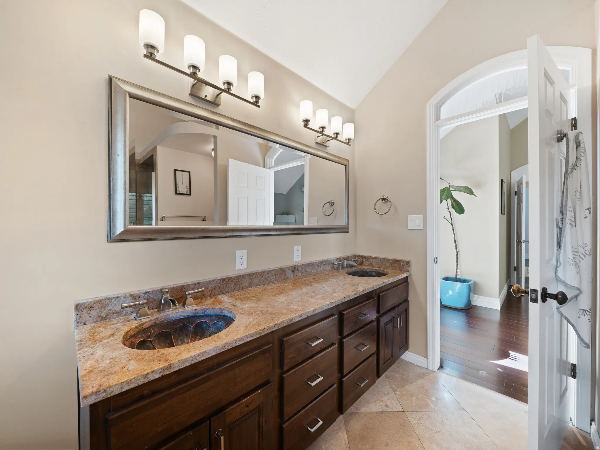 Dual vanity with dark wood cabinetry, a light-toned stone countertop, and two integrated basin sinks