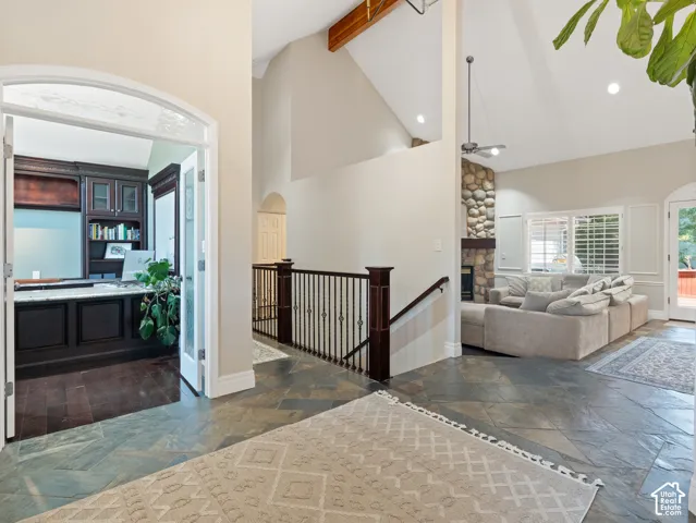 Spacious entry featuring natural stone flooring, an arched doorway, and a wrought iron railing leading to an open living area