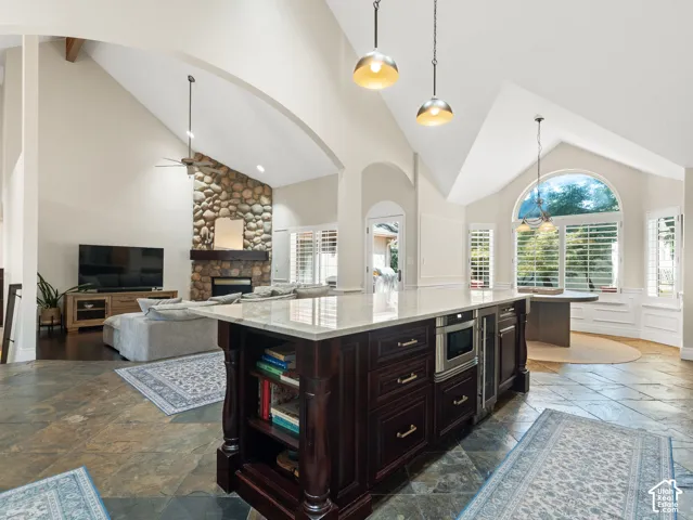 Kitchen island with dark wood cabinetry and stone countertop, featuring an integrated microwave and beverage refrigerator