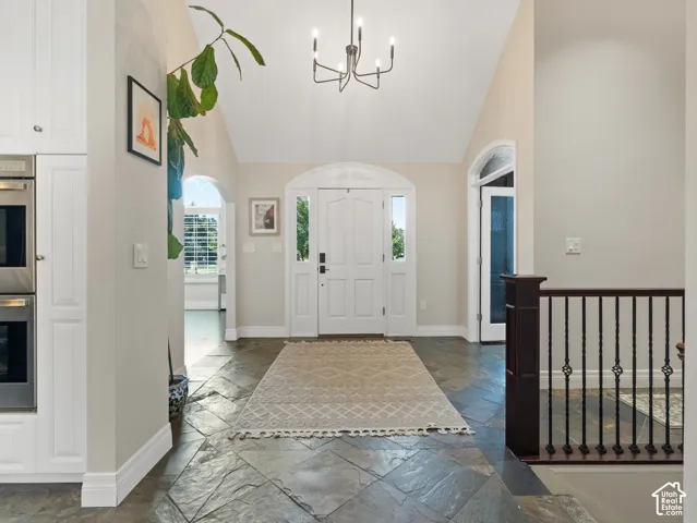 Vaulted entryway featuring slate tile flooring and a decorative chandelier