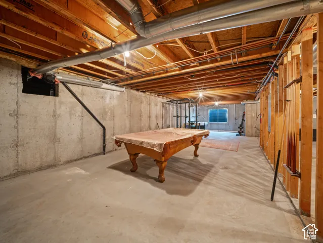 Unfinished basement featuring exposed wood joists, concrete foundation walls, and a concrete floor