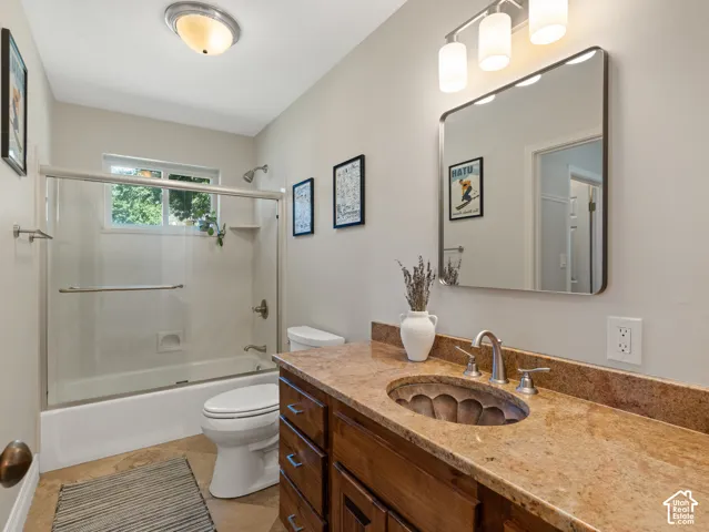 Wood-finish vanity featuring a stone countertop, an oval basin, and a brushed nickel faucet