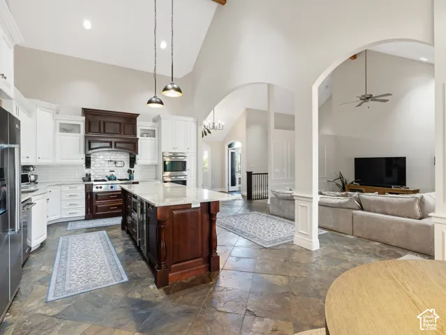 Spacious kitchen featuring an expansive center island with a light-toned countertop, contrasting dark wood cabinetry, and stainless steel appliances