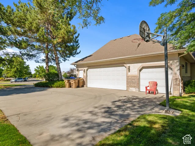 Three-car garage with two white roll-up doors and one single white roll-up door, featuring a brick facade accent