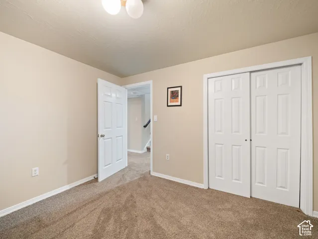 Carpeted room featuring beige walls, white baseboards, a six-panel door, and a two-door bypass closet