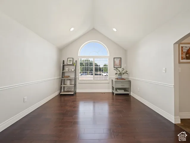Vaulted ceiling with recessed lighting, arched transom window, wood-finish flooring, and chair rail molding