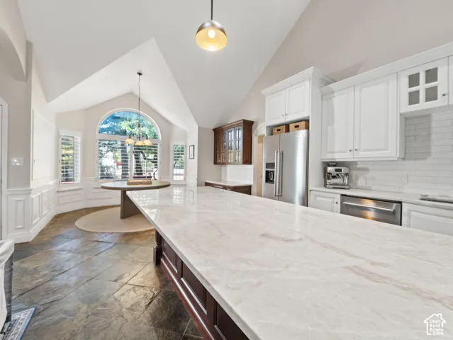 Kitchen featuring a vaulted ceiling and a large island with a light-toned countertop