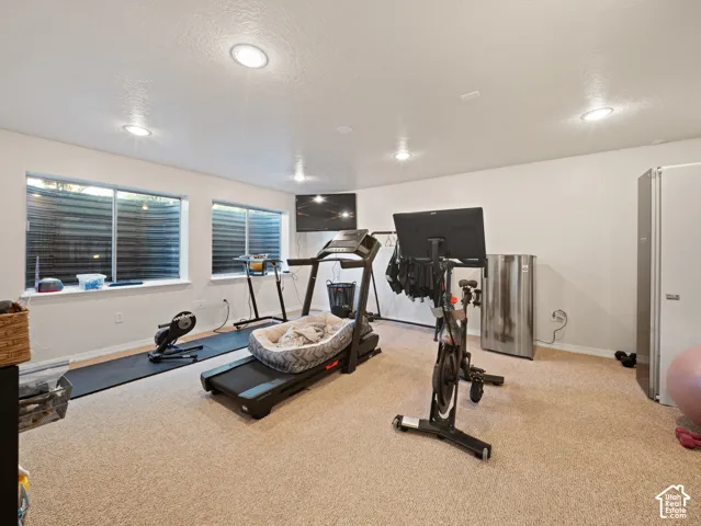 Finished basement space featuring recessed lighting, a neutral carpet, two egress windows with horizontal blinds, and painted white walls