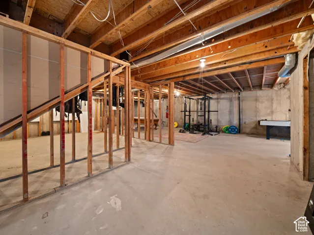 Unfinished basement featuring exposed wood joists and a concrete floor