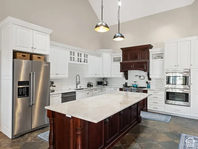 Kitchen featuring a large central island with a light-toned countertop, contrasting dark wood cabinetry, and pendant lighting