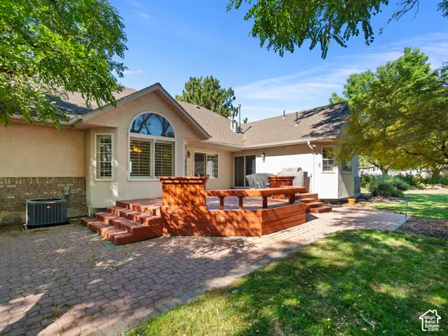 Expansive backyard featuring a multi-level wood deck, a patio with brick pavers, and a manicured lawn