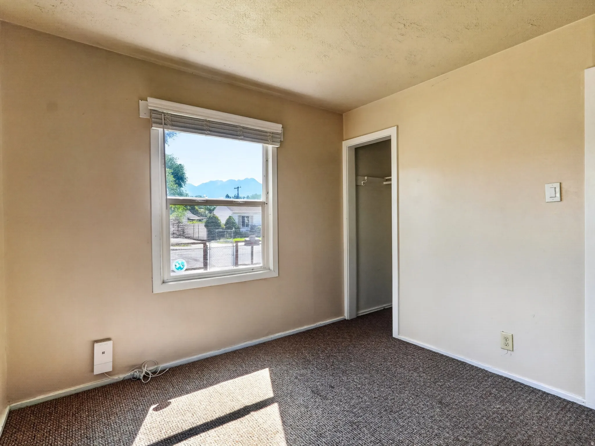 Carpeted room featuring a window with integrated blinds, providing natural illumination and distant mountain scenery