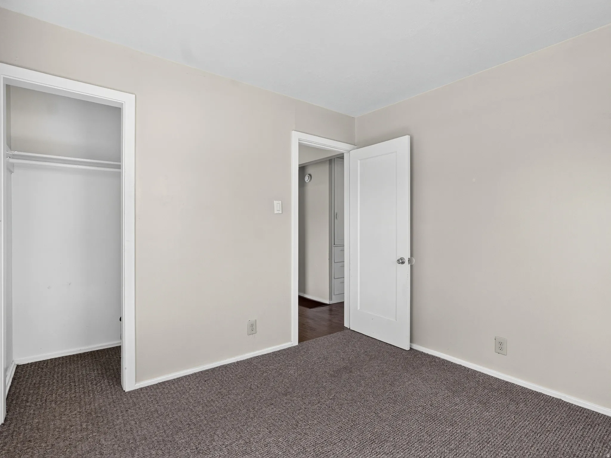 Carpeted room featuring light neutral walls and white baseboards