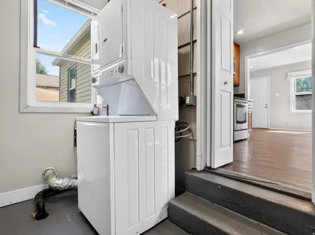 Stackable laundry appliances with a front-loading washer and dryer, set on a dark-toned floor