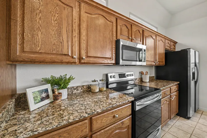Warm oak cabinetry with raised-panel doors pairs with speckled granite countertops and stainless steel appliances in this galley-style kitchen