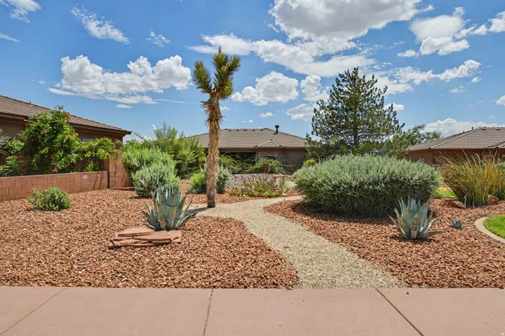 Landscaped front yard featuring a crushed rock pathway, diverse desert plantings, and a mature yucca tree
