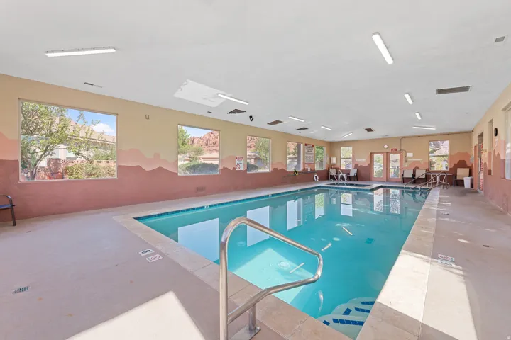 Indoor swimming pool featuring crystal-clear water, stainless steel handrails, and a spacious deck with non-slip flooring