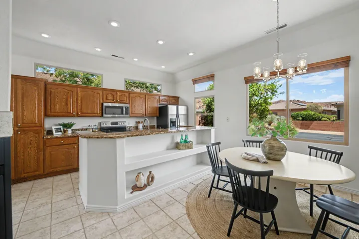 Kitchen and dining area featuring wood cabinetry, stainless steel appliances, granite countertops, and tile flooring